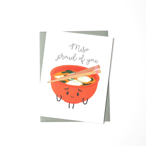 Congratulations card with an illustration of a bowl of miso with two chopsticks across the top.  The bowl of miso has arms and legs and appears to wearing an expression of pride.