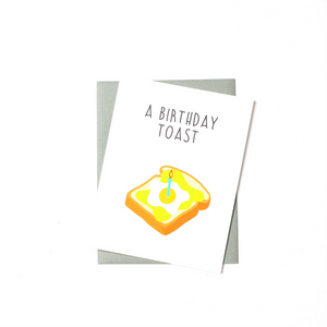 birthday card with illustration of a slice of avocado toast with a friend egg on it and one birthday candle in the center of the toast.
